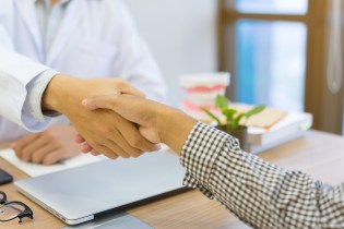 close up dentist hand shake with DSO owner after selling their practice at office desk with