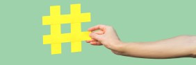 Close-up of hand holding large yellow hashtag sign