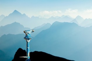 Beat-up blue standing monocular overlooking a blue mountain range.