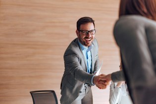 Cheerful male job candidate shaking hands with female interviewer.