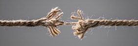 Two pieces of frayed rope connected by a single thread