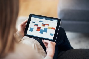 Blonde woman with long hair checking her weekly work schedule with colorful meeting blocks on her tablet.