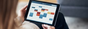 Blonde woman with long hair checking her weekly work schedule with colorful meeting blocks on her tablet.