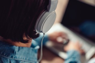 Woman with Beats headphones listening to podcasts while on laptop.