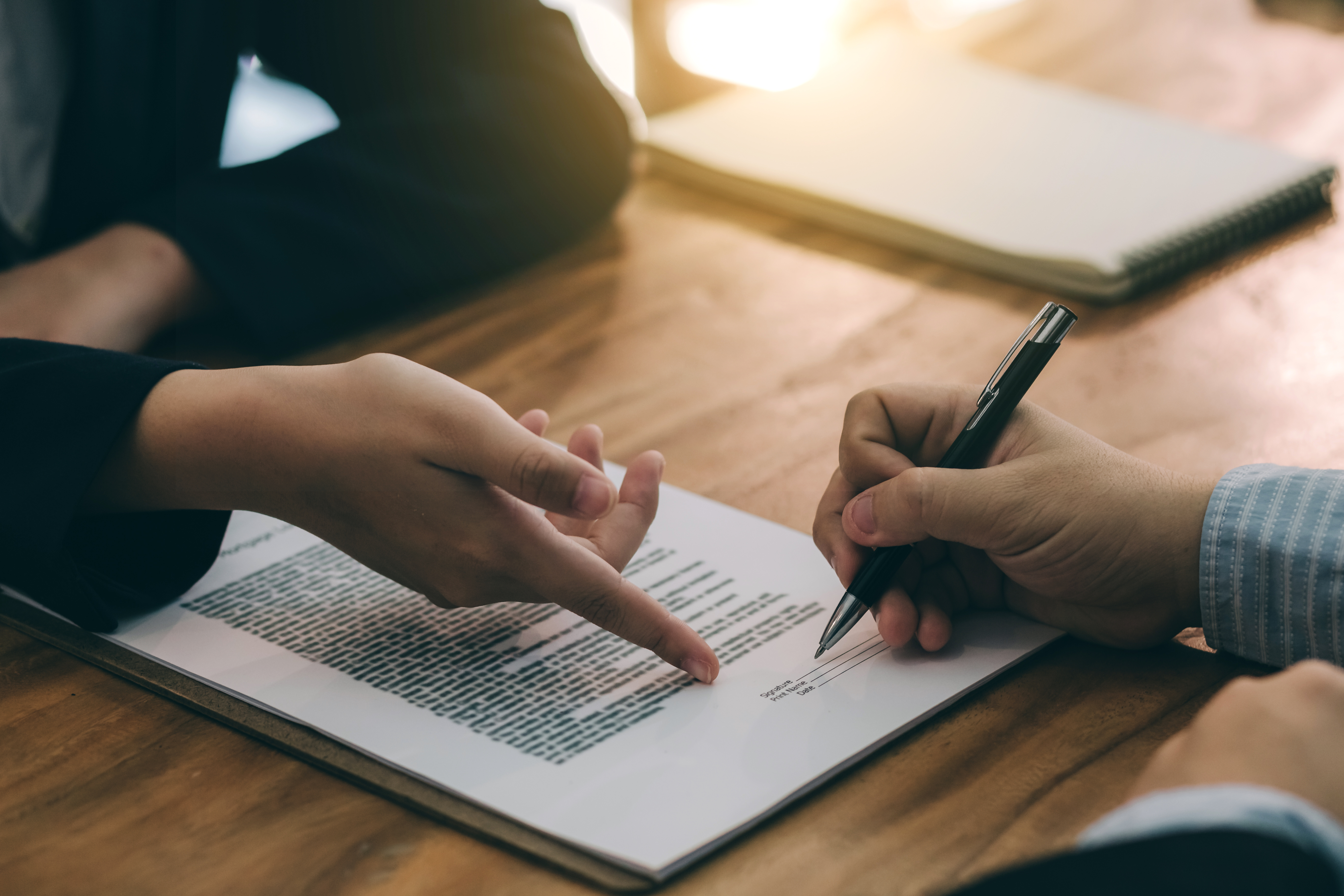 man signing real estate contract with a pen