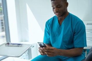 man in scrubs reading best dental blogs on his phone