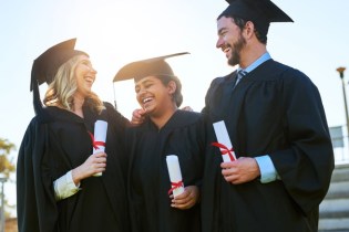three graduates in caps and gowns looking up nursing scholarships and grants