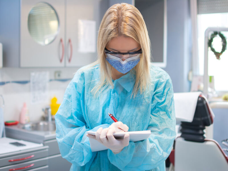 dental hygienest taking notes in scrubs