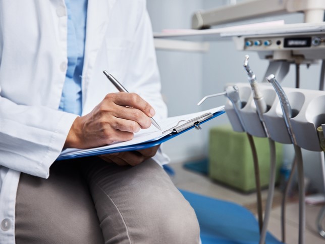 dentist writing a dental incident report on a clipboard