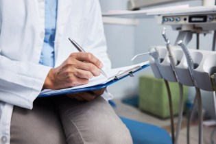 dentist writing a dental incident report on a clipboard