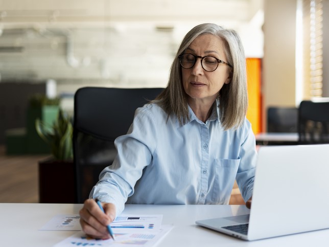 woman writing on paper looking at computer researching what insurance needed for tax preparers