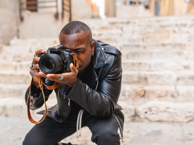 man holding a camera to his face crouching | General Liability Limit FAQs