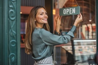 Woman hanging up an open sign outside her business while she thinks about BOP vs GL